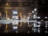 Trucks wait in line to unload their containers onto a container ship docked at the the Xiamen Songyu Container Terminal at night in Xiamen, China.