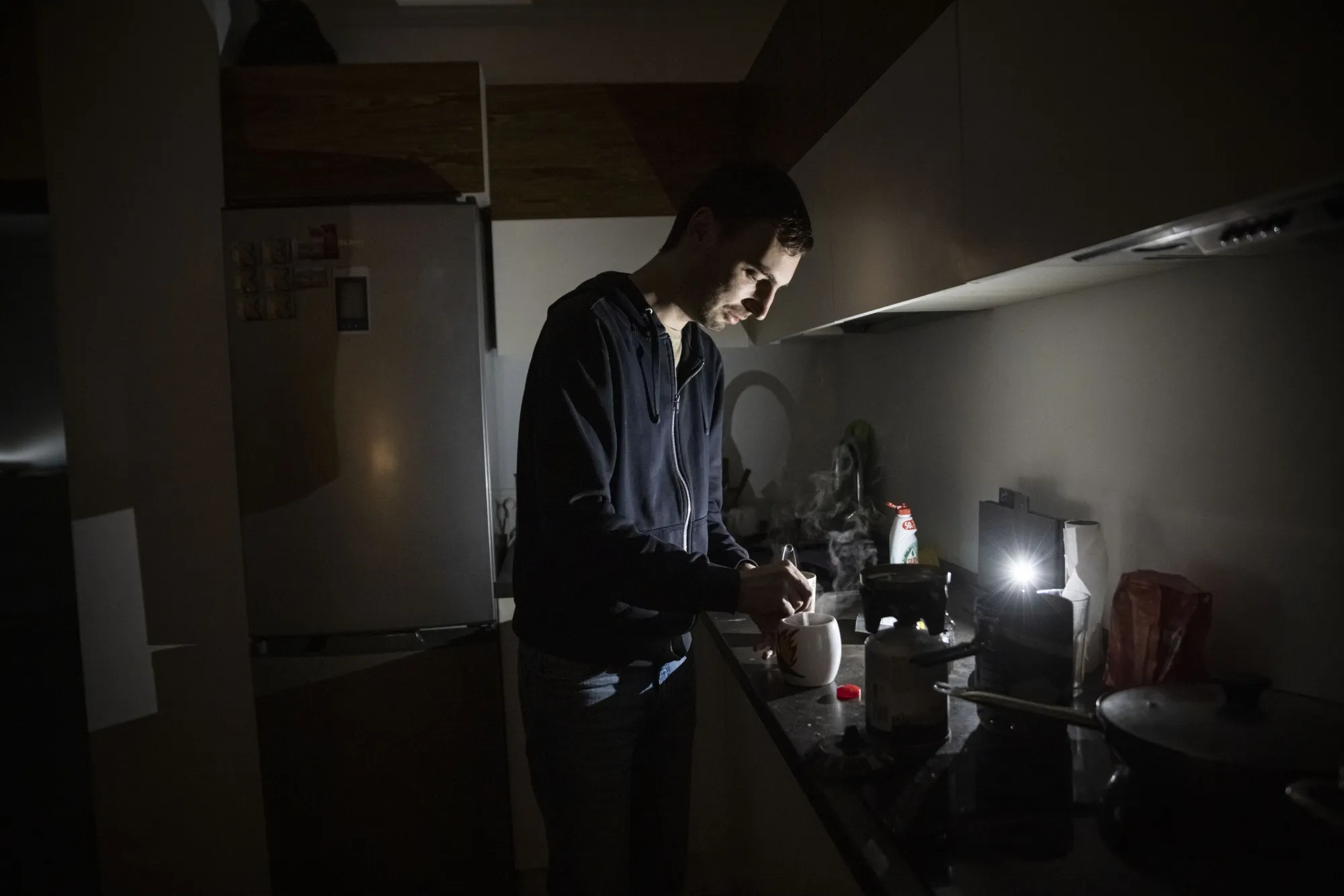 A resident makes tea using a camping stove in his apartment block&nbsp;during a power outage in Kyiv.
