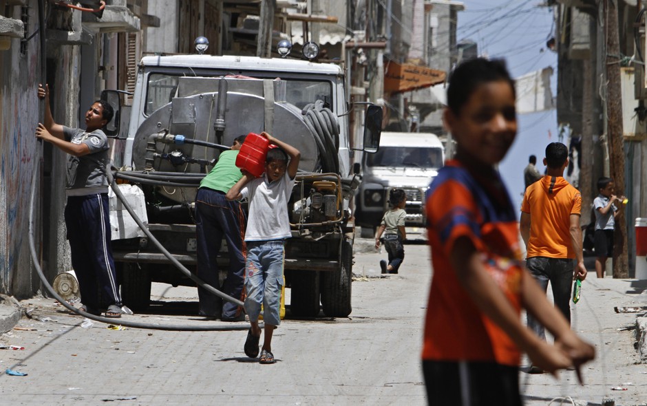 A Palestinian youth carries a container with drinking water at Shati refugee camp in Gaza City.