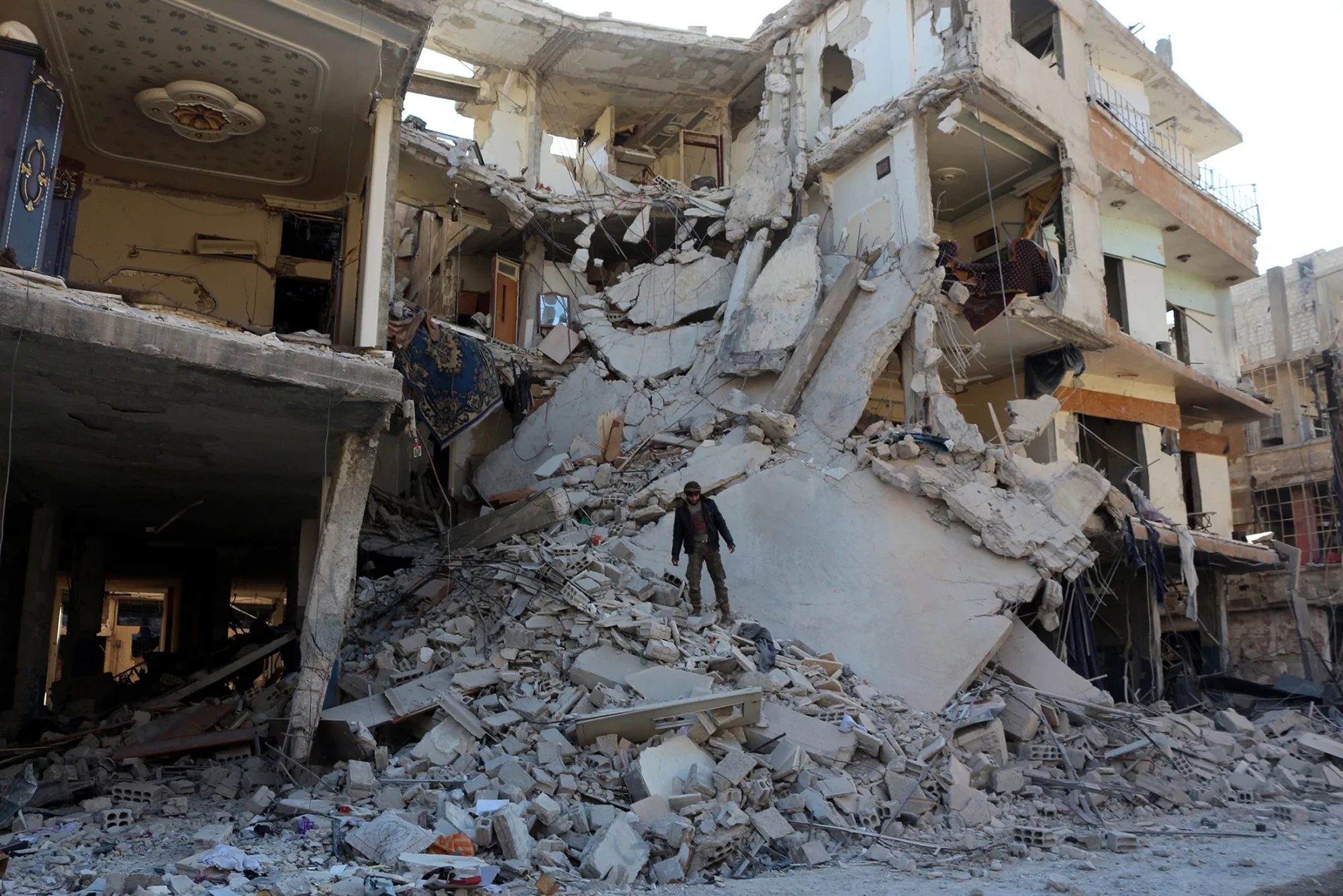 A man stands on the debris of a collapsed building after airstrikes in Damascus, Syria, on Dec. 25, 2015.
