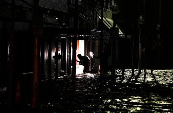 People use phone torches as they walk through a flooded street in Fort Myers, Florida, on Oct. 9.