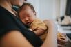Close up of a loving young Asian mother carrying her sleeping newborn baby daughter in arms at home. Bonding moment of mother and daughter. Motherhood. Love, care and tenderness