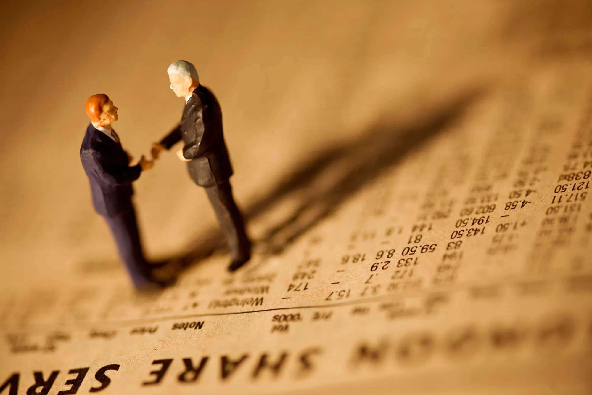 Miniature businessmen standing on financial newspaper