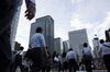 Commuters cross a road near commercial buildings in the central business district of Tokyo, Japan.