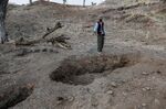 A man&nbsp;stands over several large holes that mark the locations of mass graves&nbsp;that are in the process of being excavated in the town of Adi Selam,&nbsp;in Welkait, Ethiopia on April 7.&nbsp;