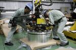 Employees operate machinery to stack coils of aluminum strip for packaging at the Tokiwa Koutai Co. processing plant in Tokyo.