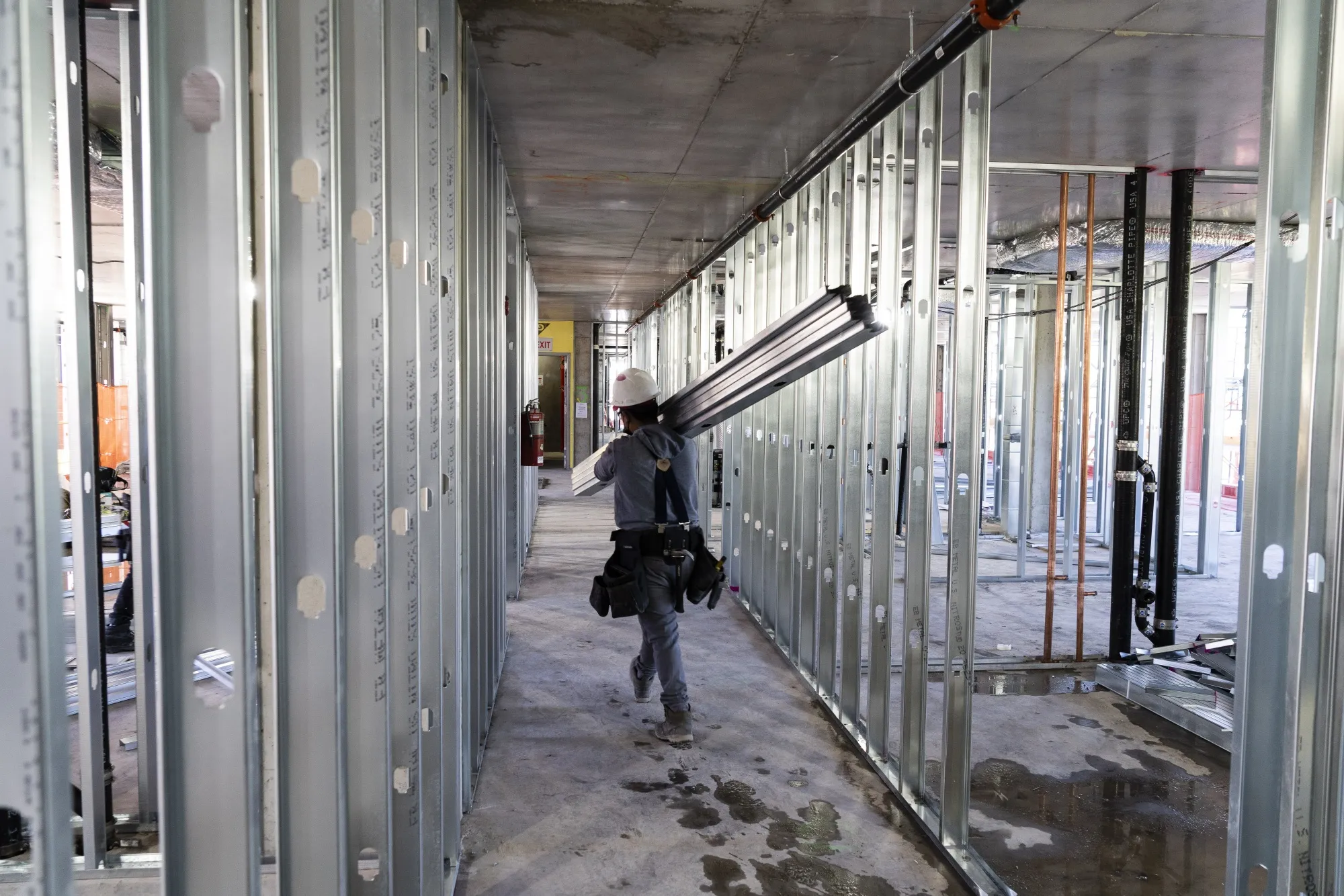 A contractor carries metal studs at a commercial development under construction in the Brooklyn borough of New York.