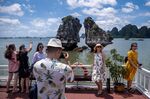 Tourists pose for photographs on a boat touring Ha Long Bay.