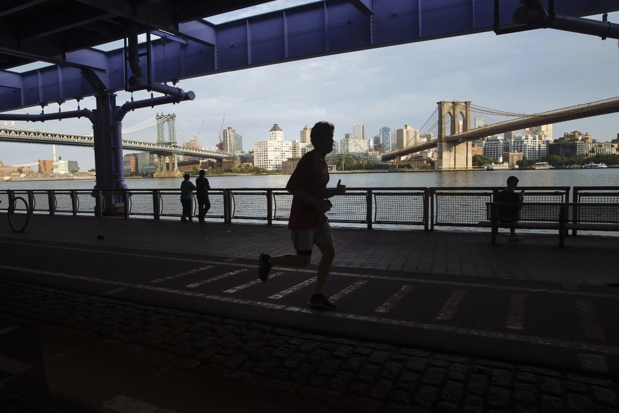A person runs&nbsp;along the East River Running Path in between the Manhattan Bridge and Brooklyn Bridge in lower Manhattan.