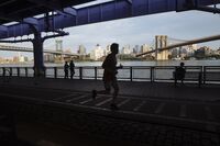A person runs along the East River Running Path in between the Manhattan Bridge and Brooklyn Bridge in lower Manhattan.