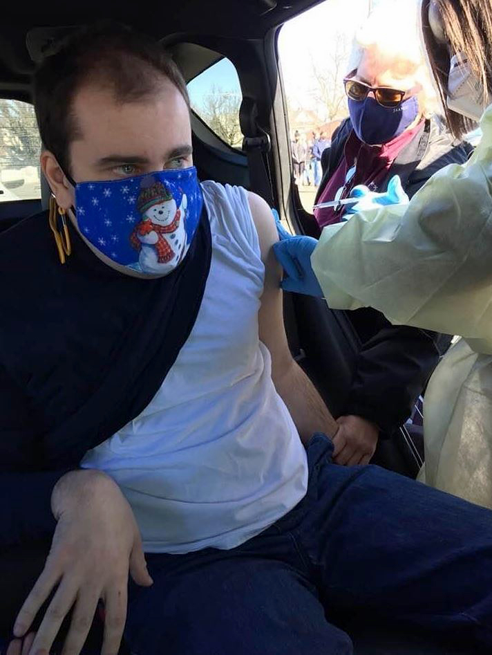 Evan Hookey, 29, of Princeton, New Jersey, receiving his first Covid-19 vaccination from a mobile unit operating at Trenton Central High School. The in-vehicle shot cuts wait time and potential virus exposure for people like Evan, with autism, and others with physical and developmental disabilities.