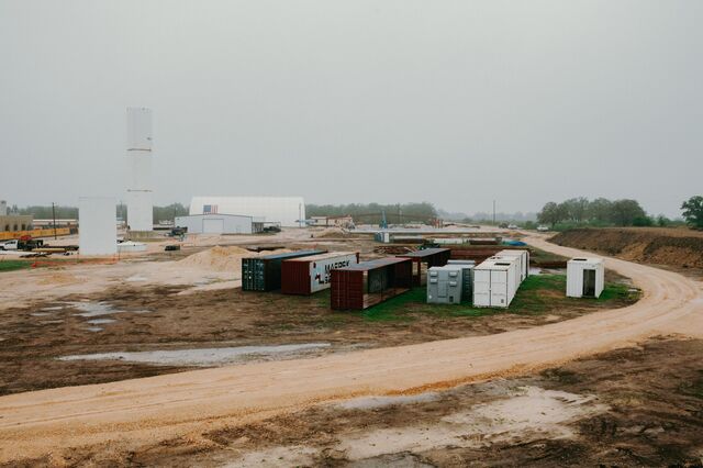 Shipping containers on a muddy dirt ground at  Proto-Town while under development. 