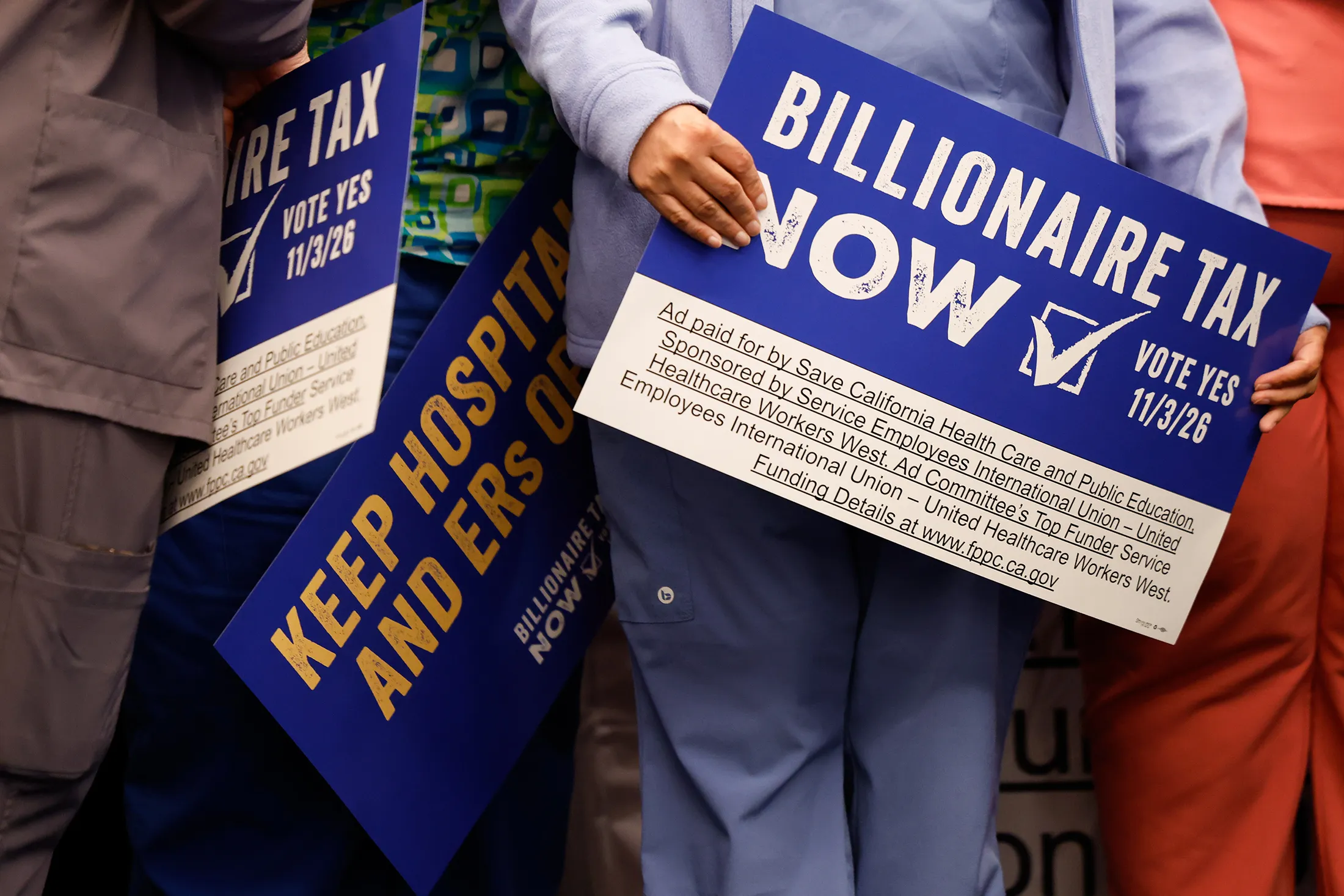 Supporters hold signs advocating for the Billionaire Tax Now coalition during a news conference in Los Angeles in April.