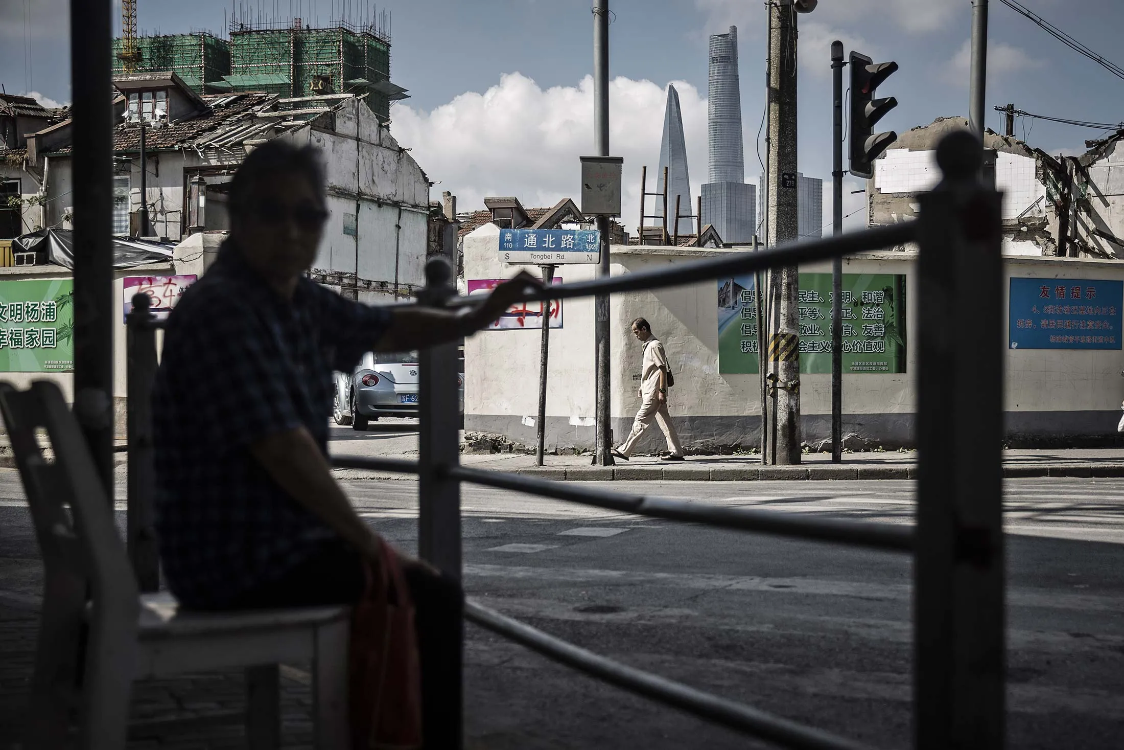 A pedestrian walks through a neighborhood slated for redevelopment as the Shanghai Tower stands in the distance in Shanghai.
