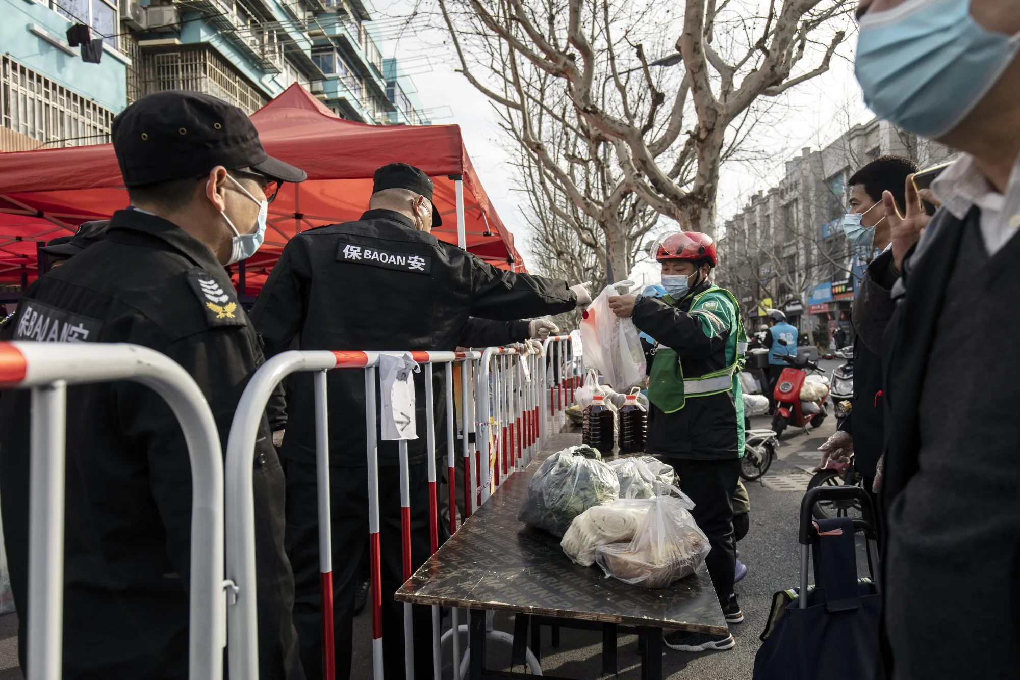 A security guard helps transport deliveries of food from a courier to Shanghai residents under lockdown.