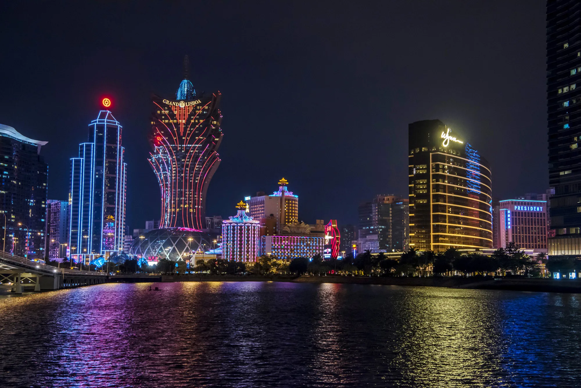 Bank of China Ltd. building, second left, Casino Grand Lisboa, operated by SJM Holdings Ltd., third left, and Wynn Macau casino resort, operated by Wynn Resorts Ltd., right, stand illuminated at night in Macau, China, on Sunday, Dec. 06, 2015. Casino operators in the Chinese gambling hub of Macau saw a 32 percent slump in revenue in November from a year earlier and it's fallen for 18 straight months, data from the city show.
