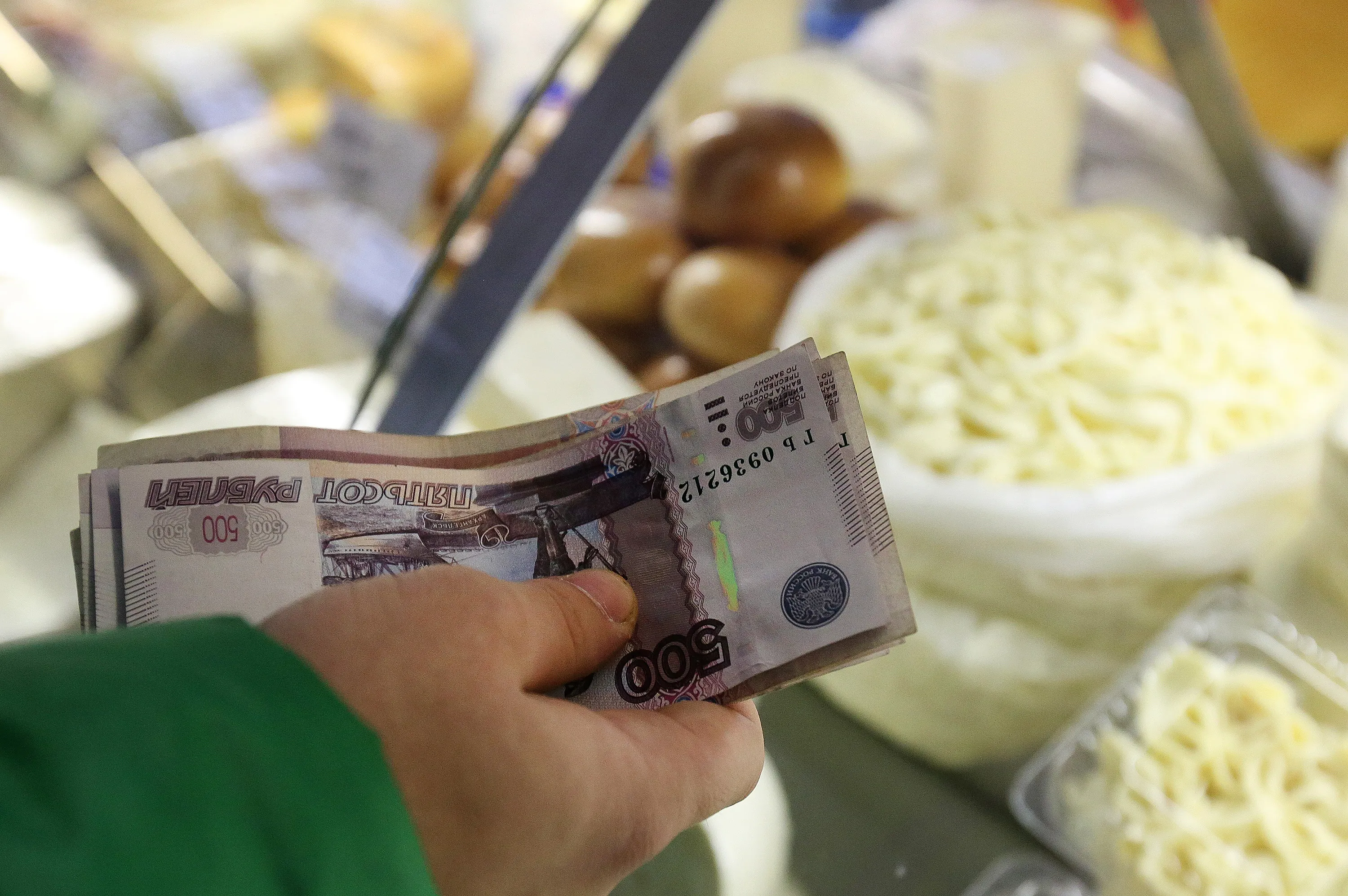 A customer counts out ruble banknotes at a stall selling dairy products inside the Dorogomilovsky food market in Moscow.
