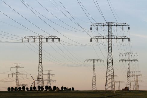 Electric power lines and pylons stand next to a wind turbine in the countryside near Berlin
