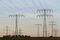 Electric power lines and pylons stand next to a wind turbine in the countryside near Berlin. Germany must spend at least 22 billion euros on its power network by 2025 to cope with the biggest clean-energy push of any industrialized nation, the country’s four grid managers said in November. Photographer: Michele Tantussi/Bloomberg