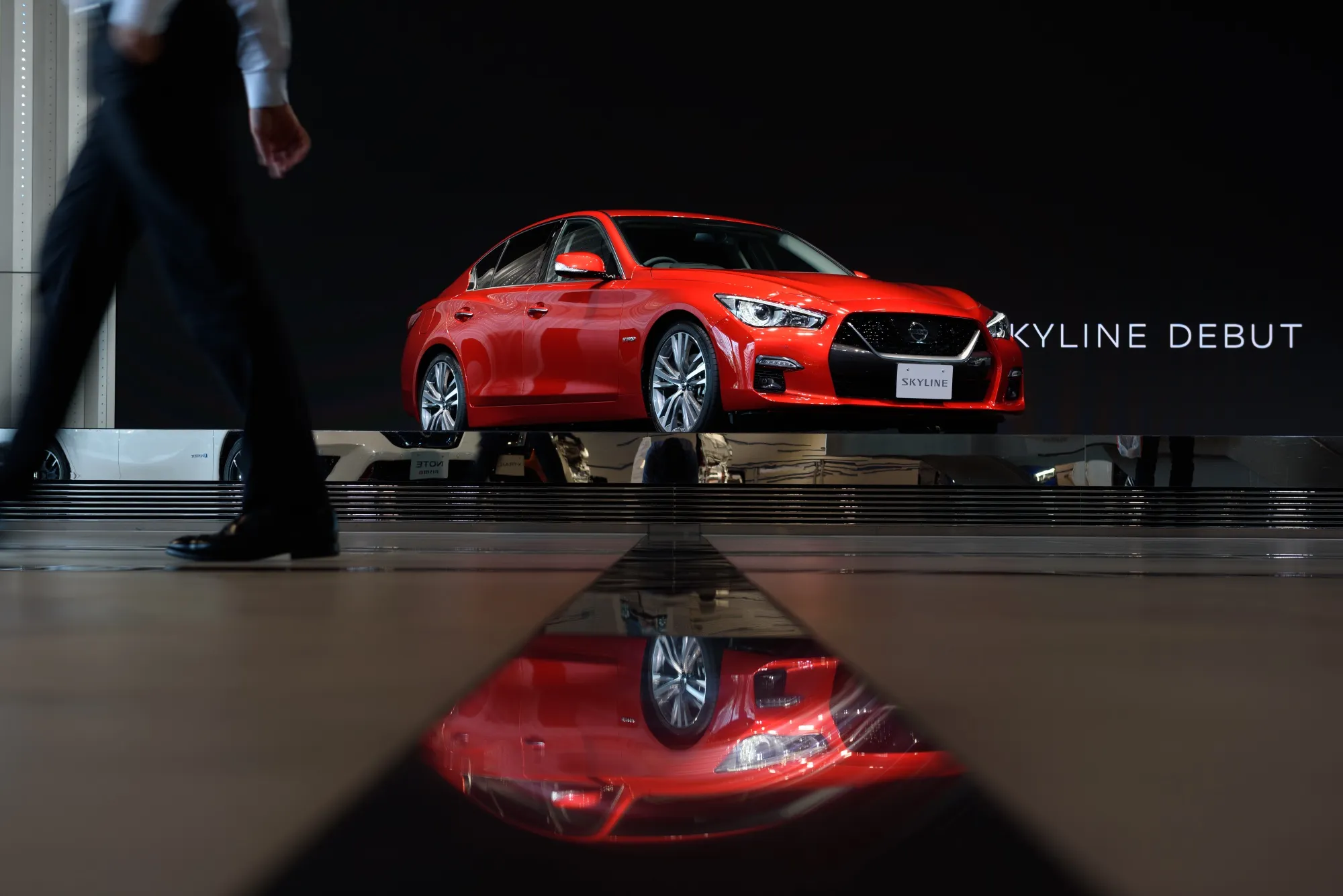 A visitor walks past a Nissan Motor Co. Skyline vehicle on display at the company's headquarters in Yokohama.