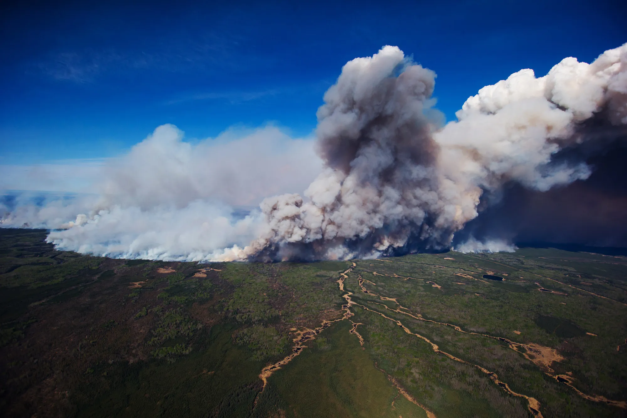 A huge plume of smoke from wildfires burning rises over Fort McMurray in this aerial photograph taken in Alberta, Canada, on Friday, May 6, 2016.&nbsp;