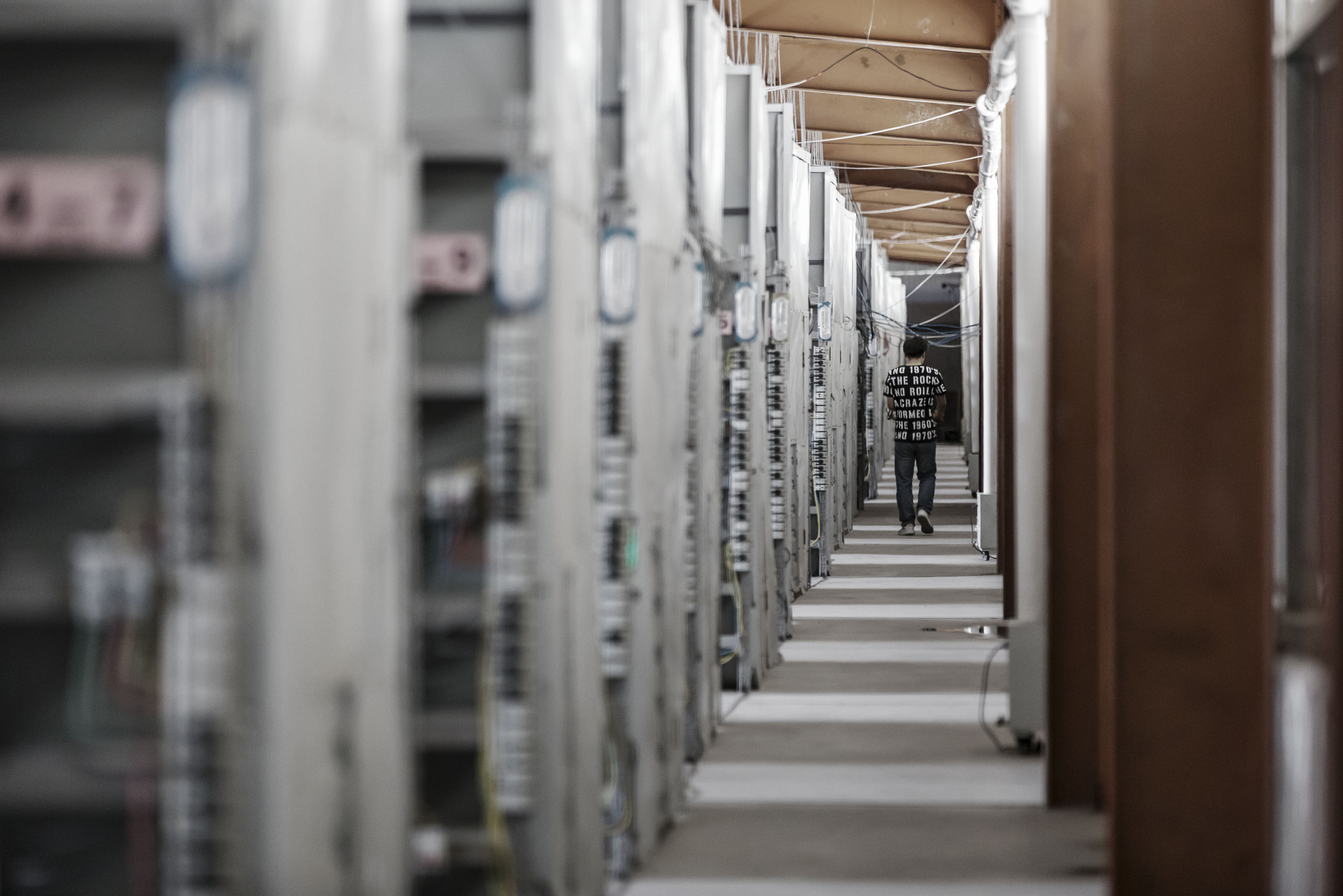 A technician walks past shelves containing bitcoin mining machines in Ordos, Inner Mongolia, China.
