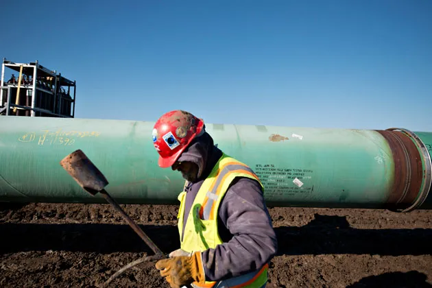 A worker carries a torch after heating a pipe joint during construction of the Gulf Coast Pipeline Project in Atoka, Okla.