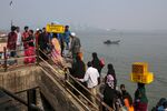 Passengers disembark from a boat beyond Jawaharlal Nehru Port in the distance in Navi Mumbai, Maharashtra, India.