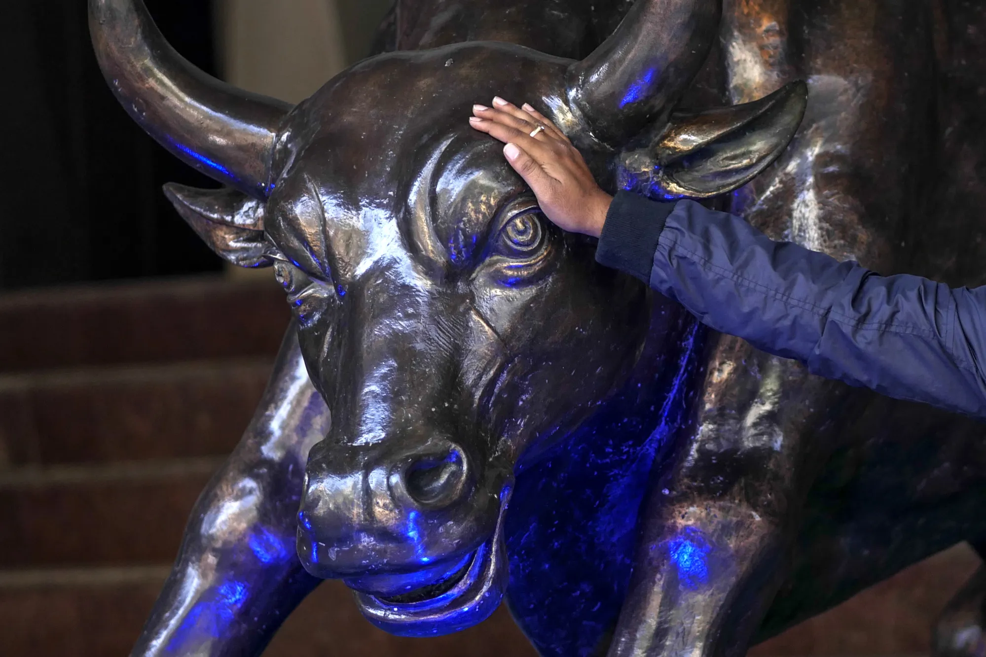 A man touches a bronze bull statue at the Bombay Stock Exchange&nbsp;in Mumbai.