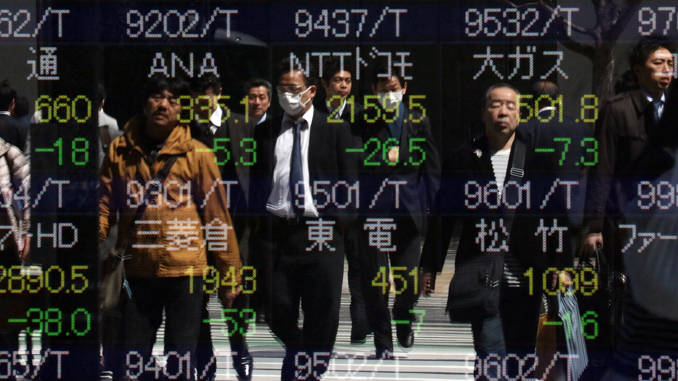 Pedestrians are reflected in the window of a securities company showing the numbers of the Tokyo Stock Exchange.

