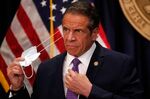 Gov. Andrew Cuomo takes off his protective face mask before speaking during a news conference in New York, on April 19. 