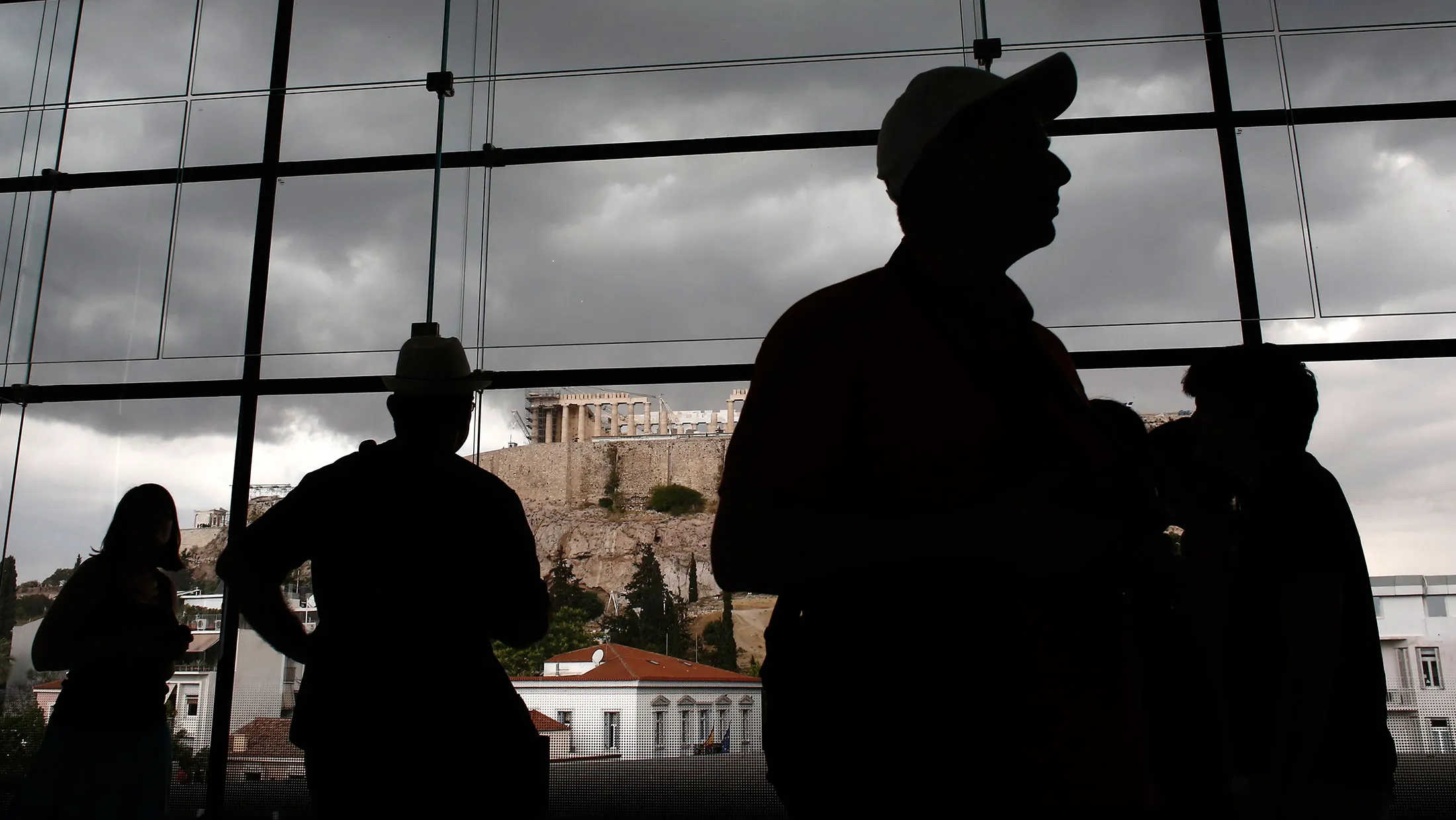Visitors pass a view of the Acropolis Hill as they walk through the Acropolis museum in Athens.

