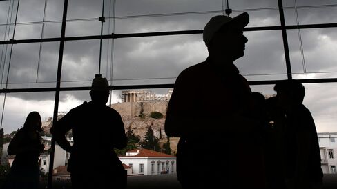 Visitors pass a view of the Acropolis Hill as they walk through the Acropolis museum in Athens.