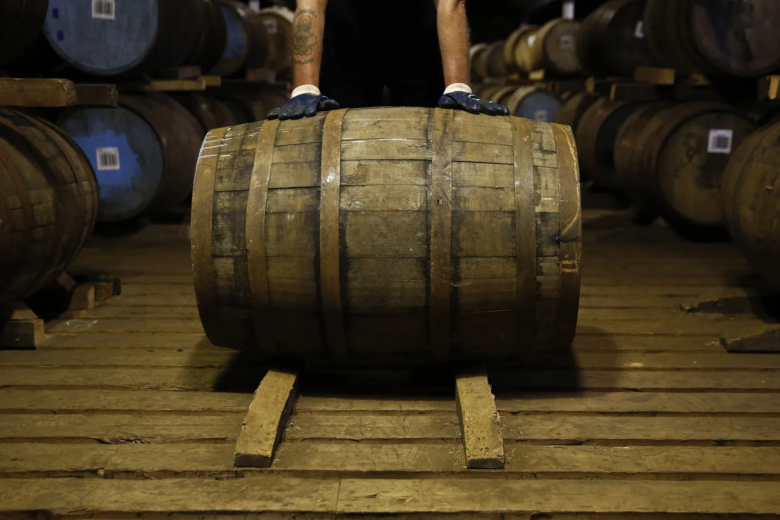 An employee moves a wooden cask of&nbsp;Scotch whisky at a distillery&nbsp;in Keith, UK.