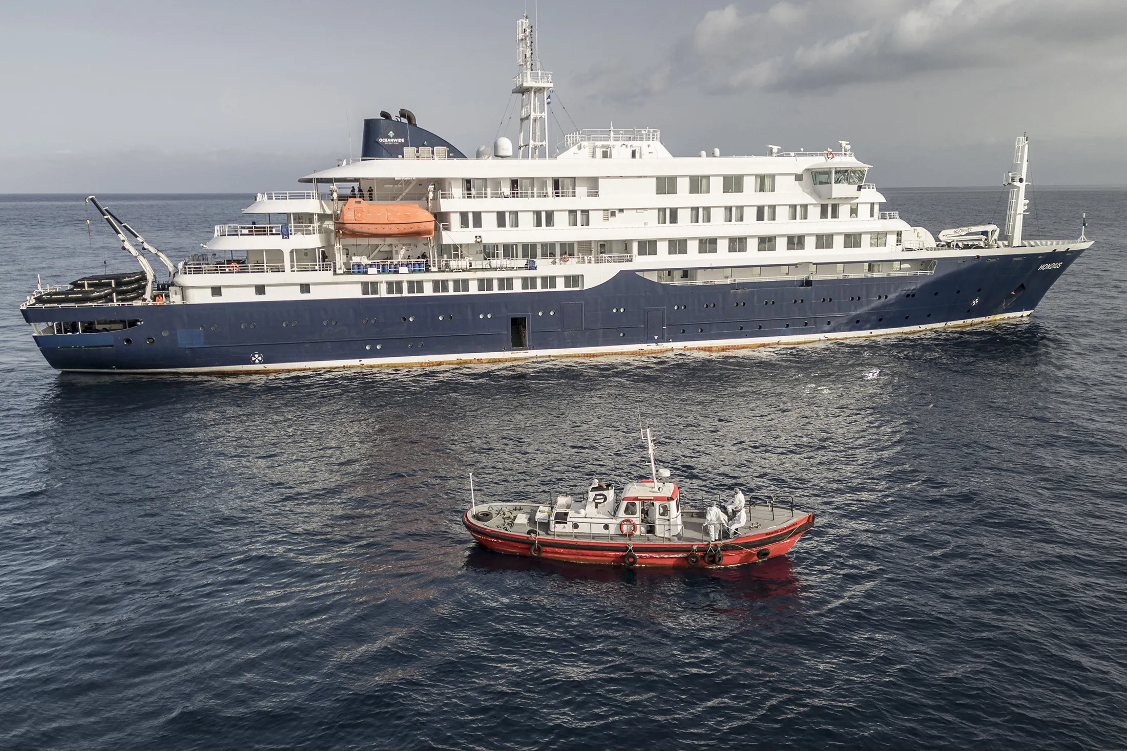 An ambulance boat carrying crew members wearing hazmat suits approaches the cruise ship MV Hondius, while stationary off the port of Praia, Cape Verde, on May 5.