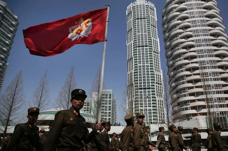 North Korean soldiers carry the Korean People's Army flag as they walk past residential buildings along Ryomyong Street in Pyongyang.