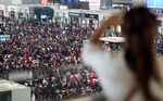 A woman looks out over the crowds as passengers wait to board their trains as they head to their hometowns for the Lunar New Year holiday, at Shanghai Hongqiao railway station in Shanghai on February 3, 2016.
