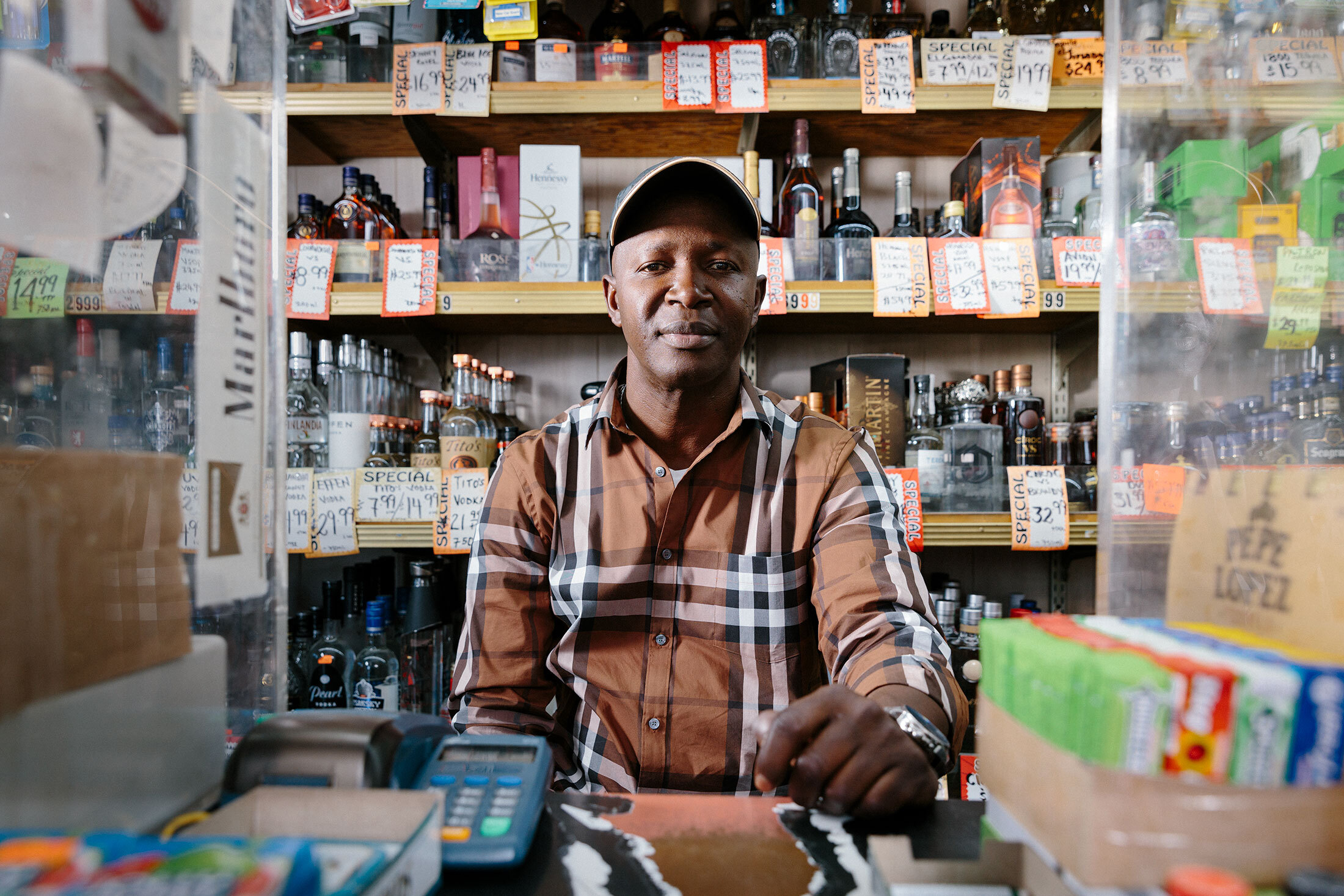 Abdul Jamal Sheriff behind the plexiglass at Holiday Liquor Market.&nbsp;