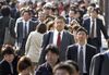 Business people walk along a sidewalk near at Shinjuku Station in Tokyo on Wednesday, November 17, 2004. Japan's Cabinet Office said it grew more pessimistic about the state of the world's second-largest economy in November for the first time in 17 months, citing slowing manufacturing and overseas demand.