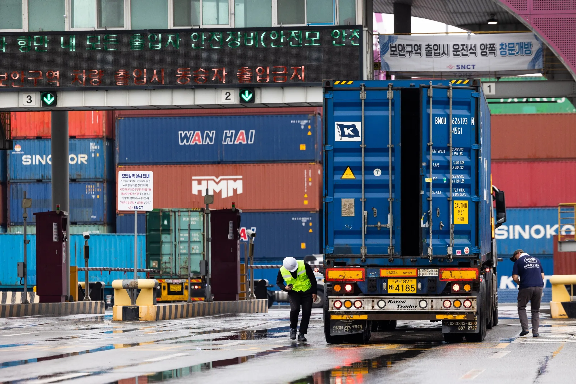 A truck driver, right, and a security guard inspect a truck at the Sun Kwang Newport in Incheon, on June 15.