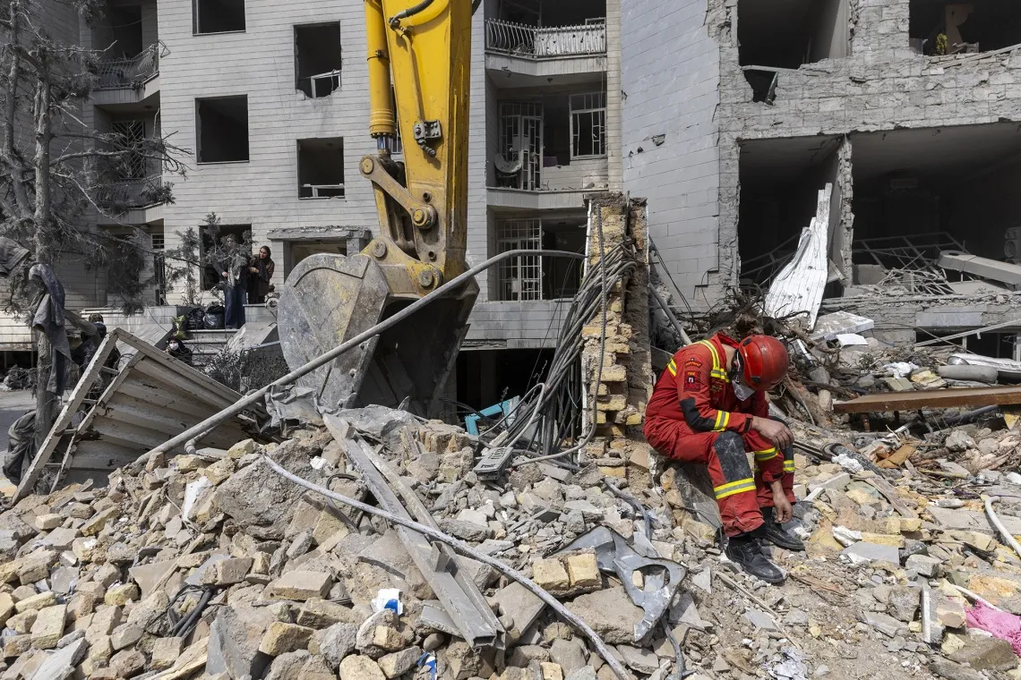 A worker sits amid the rubble of residential buildings destroyed following an attack in Tehran on March 12.