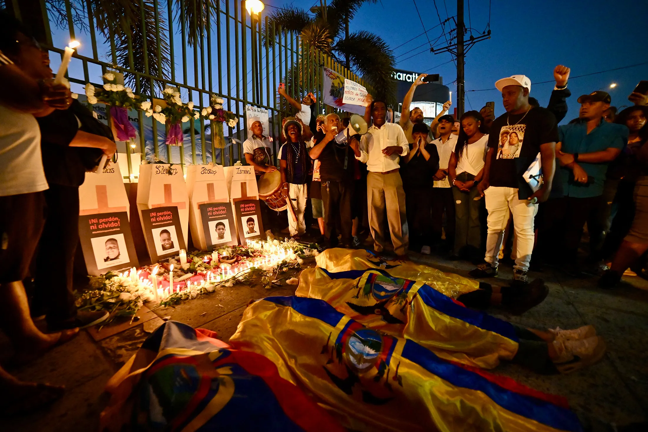 Relatives of four minors apprehended by soldiers and later found dead near a military base lie covered with Ecuadorian flags during a rally to demand justice a year after their disappearance in Guayaquil, on Dec. 8.