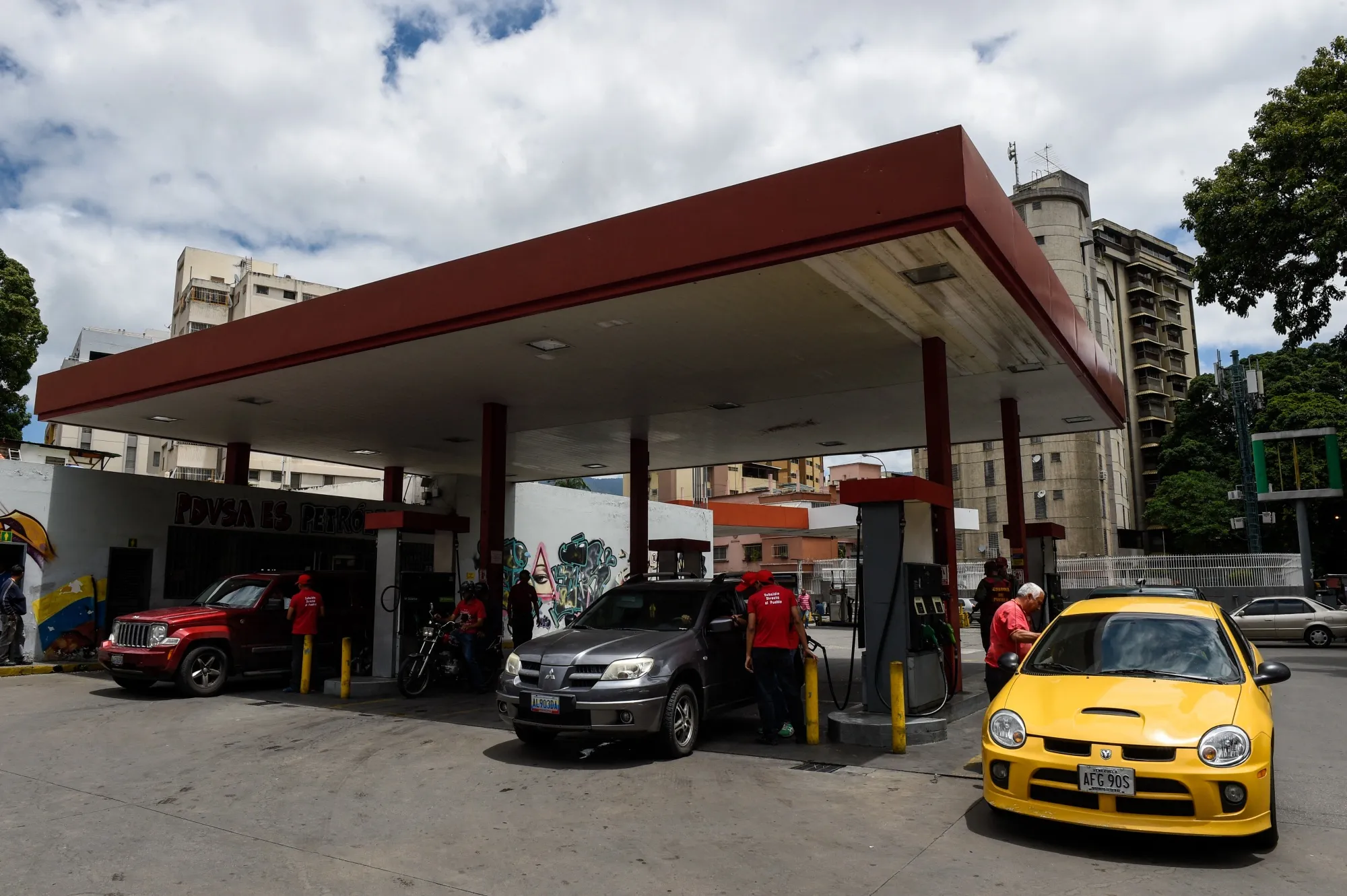 Employees pump fuel at a gas station in Caracas.