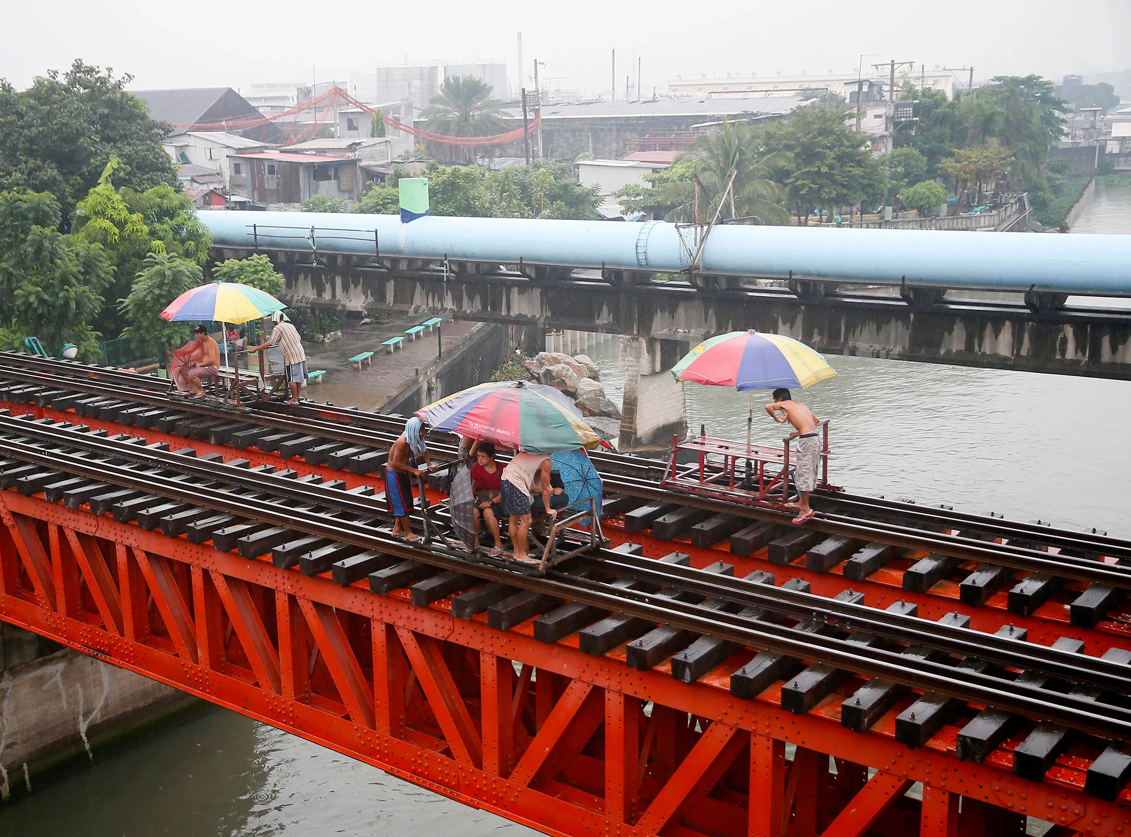 Commuters ride on a locally-built cart known as 'trolley' which makes use of a railroad track on a typhoon-induced rain on Oct.17, in Manila.
