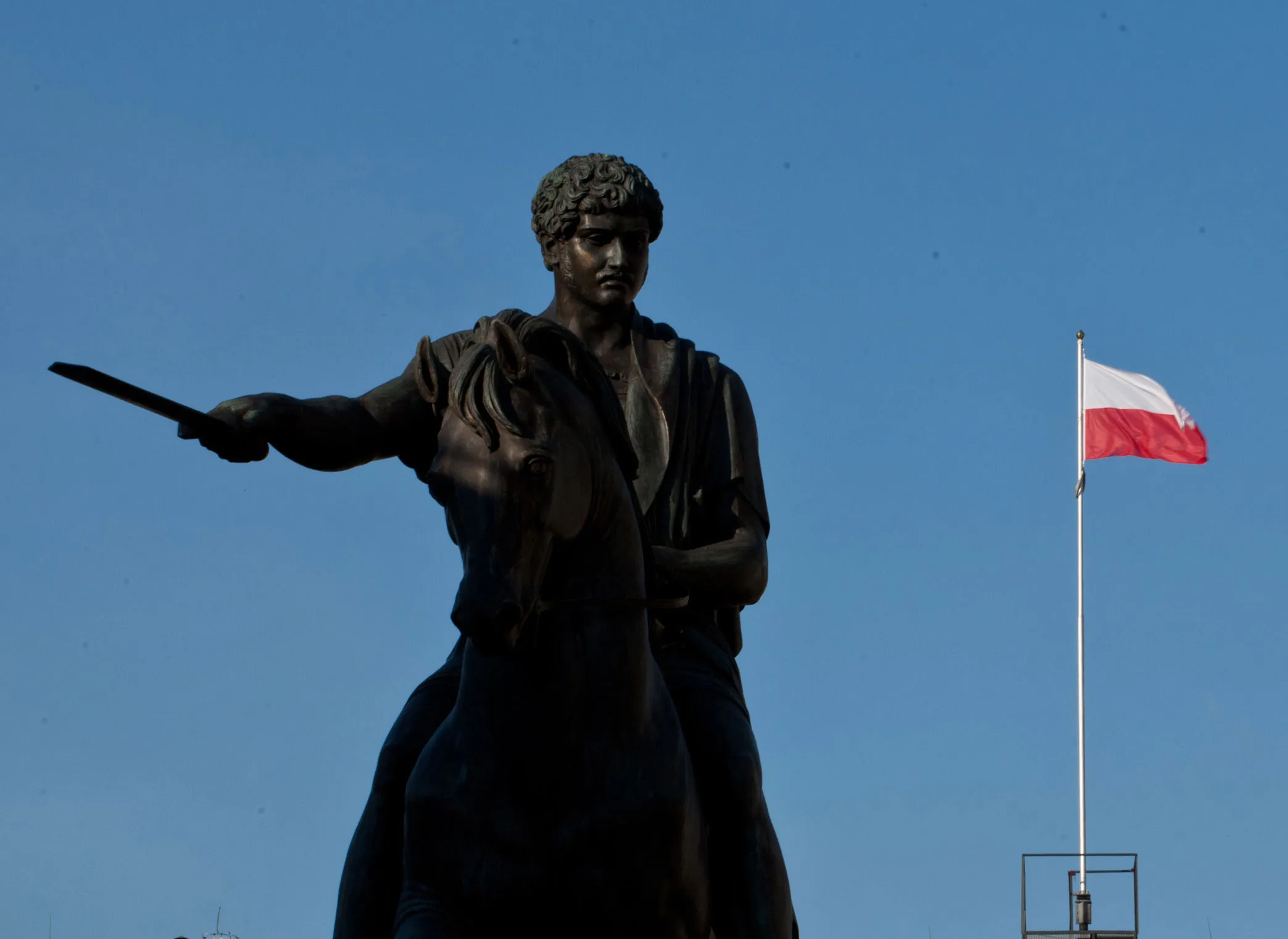 A Polish national flag flies beyond a statue of King Stanislaw Poniatowski in Warsaw, Poland.