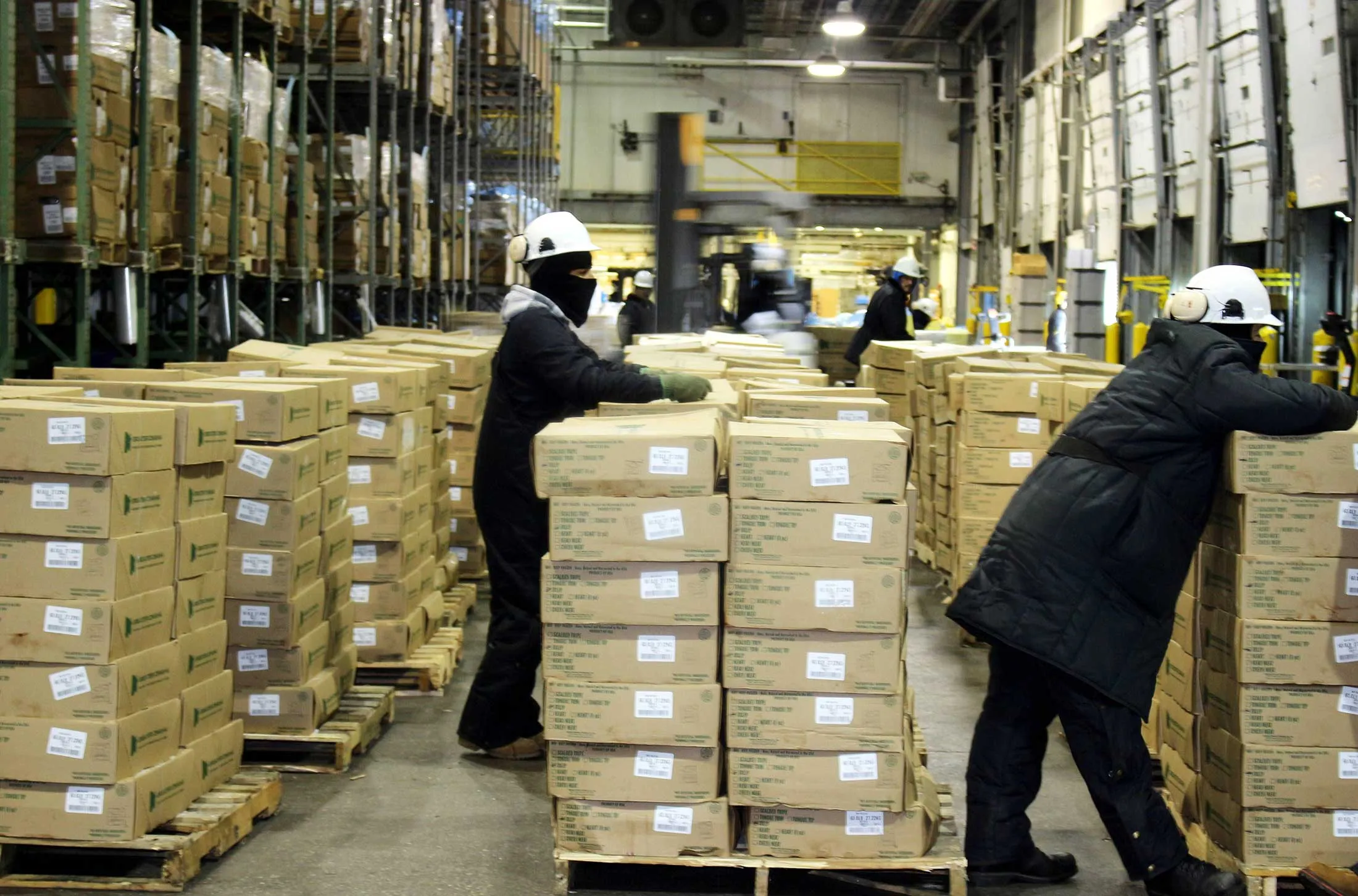 Three workers with stacks of packed beef in a warehouseat an Omaha meat processor
