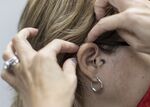 A hearing aid specialist with the Hear Again America Co. places a hearing aid on an ear on Oct. 20, 2021 in Fort Lauderdale, Florida.