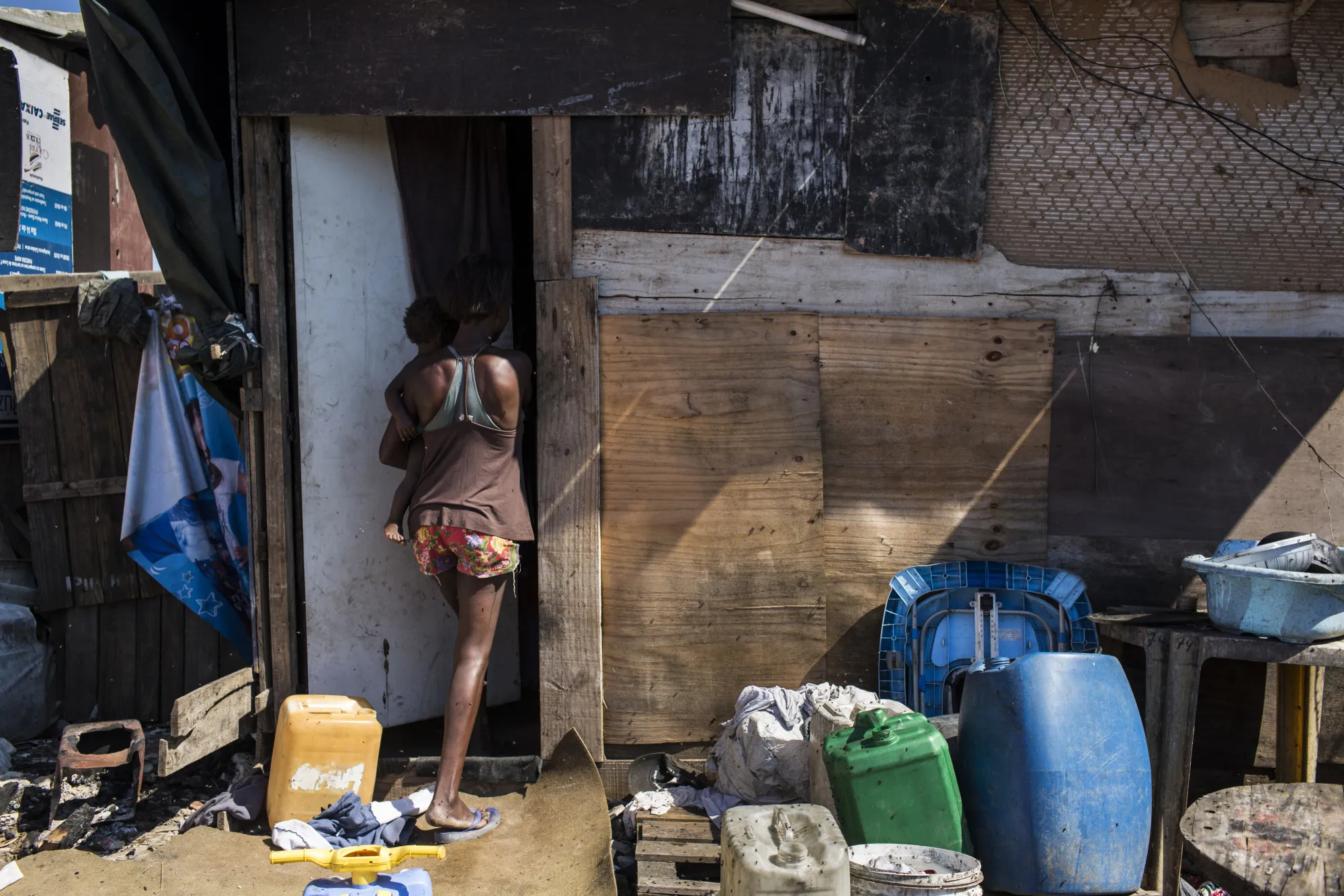 A mother and child enter a makeshift home in Rio de Janeiro.