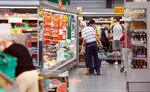 Customers browse a refrigerated aisle of food in a Morrisons supermarket in Saint Ives, UK.