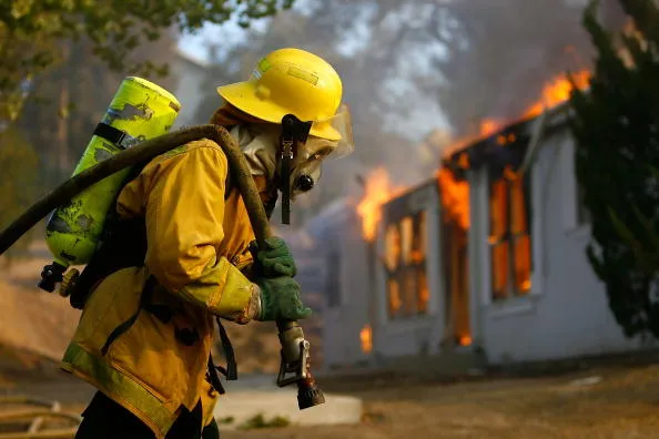 A U.S. forestry firefighter pulls a hose to a burning home in Deerhorn Valley, California in October.
